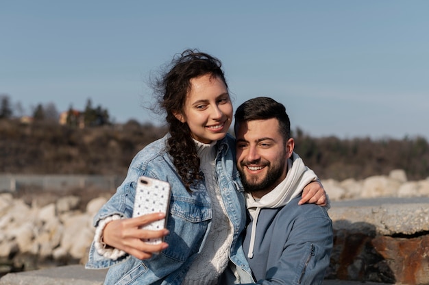 Medium shot smiley couple taking selfie