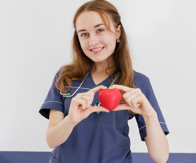 Medium shot smiley doctor holding heart shaped toy