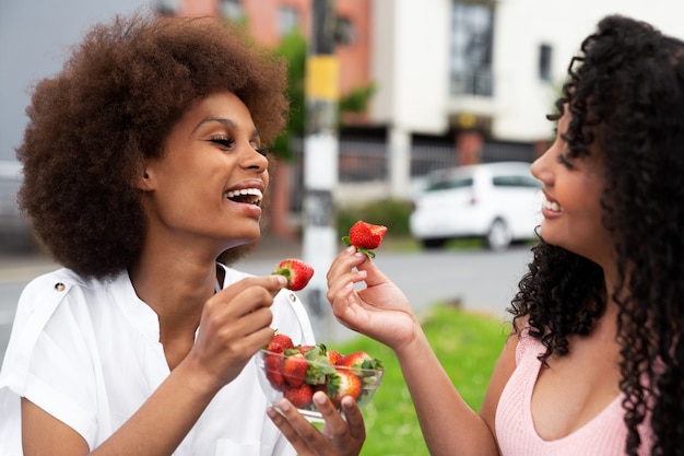 Photo medium shot smiley friends eating strawberries