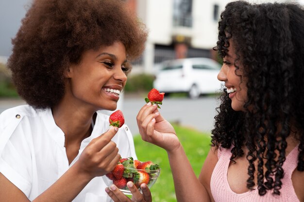 Medium shot smiley friends eating strawberries