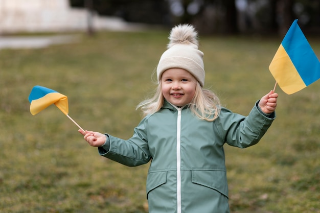 Medium shot smiley girl holding krainian flags