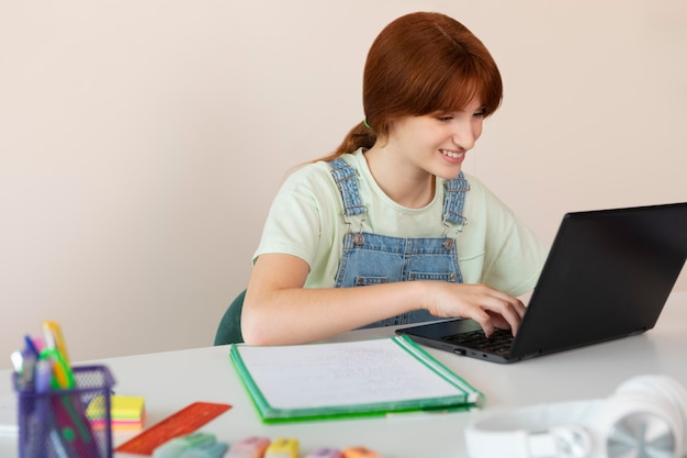 Medium shot smiley girl typing on laptop