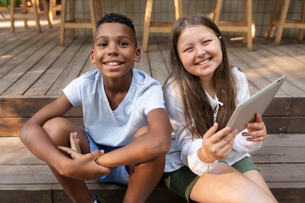 Medium shot smiley kids with tablet