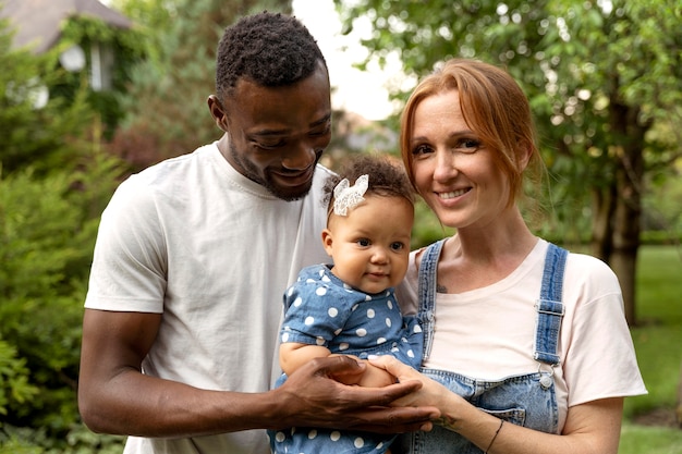 Medium shot smiley parents holding baby