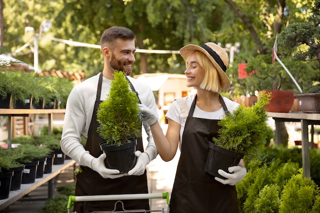 写真 植物を運ぶミディアムショットの笑顔の人々