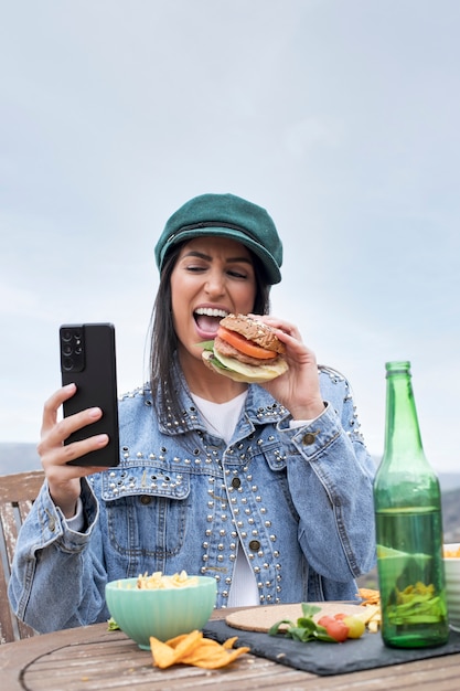 写真 ハンバーガーを食べるミディアムショットスマイリー女性