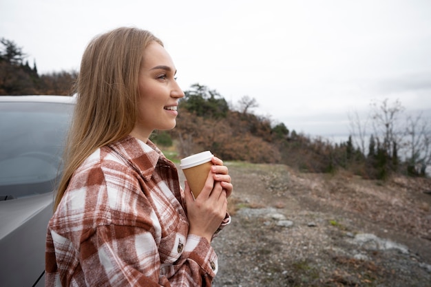 コーヒーカップを保持しているミディアムショットスマイリー女性