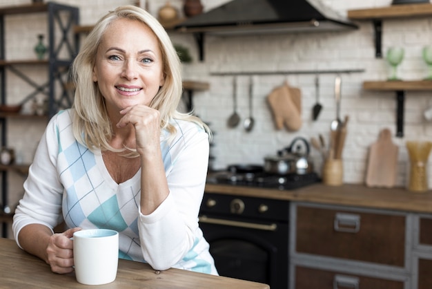 Medium shot smiley woman holding a mug