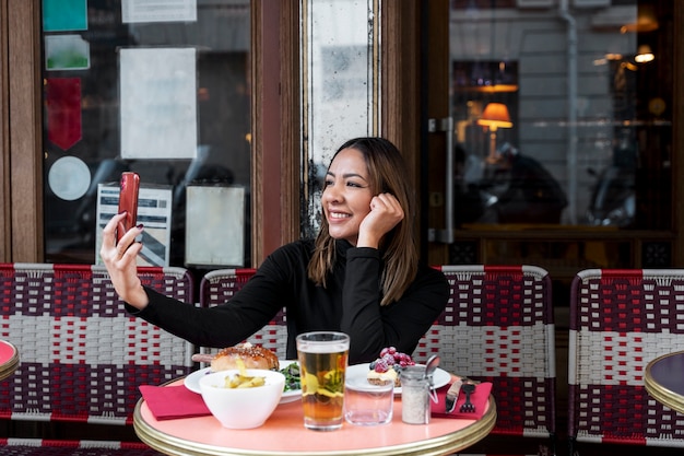 Medium shot smiley woman taking selfie