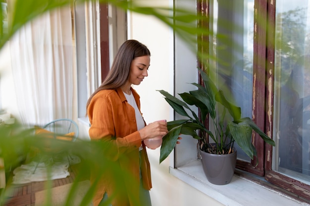 Medium shot smiley woman watering plant