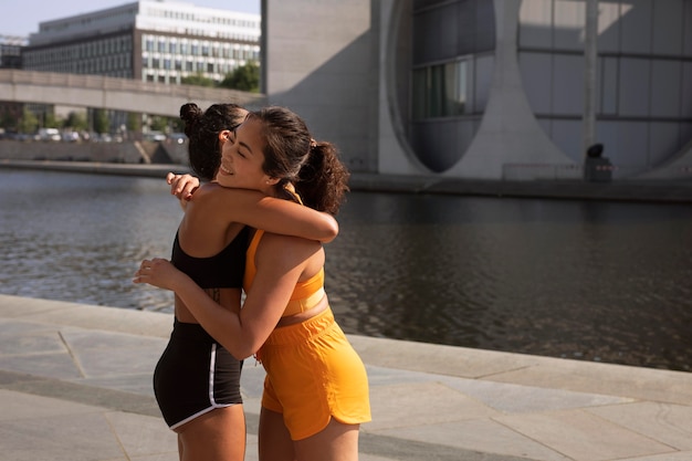 Medium shot sportieve vrouwen knuffelen