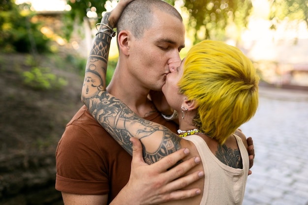 Татуированные люди среднего плана целуются