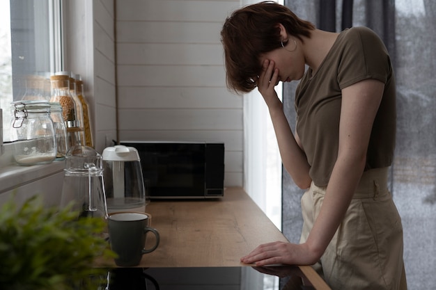 Medium shot trieste jonge vrouw in de keuken