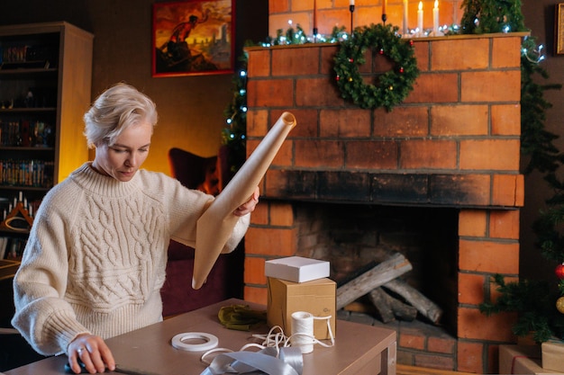 Medium shot van aantrekkelijke jonge vrouw die inpakpapier voorbereidt om geschenkdozen met kerst in te pakken