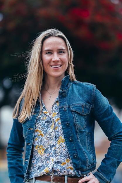 Medium shot of a vertical portrait of smiling blonde woman with denim jacket