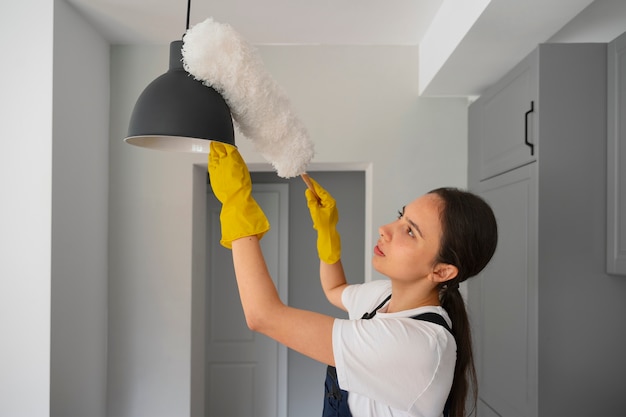 Foto donna del colpo medio che pulisce casa