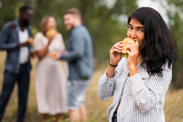 写真 ハンバーガーを食べるミディアムショットの女性