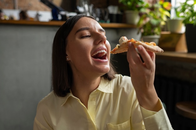 Женщина среднего выстрела ест вкусную пиццу