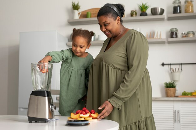 Medium shot woman and girl preparing smoothie