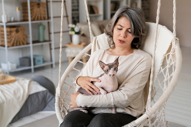 Medium shot woman holding cat indoors