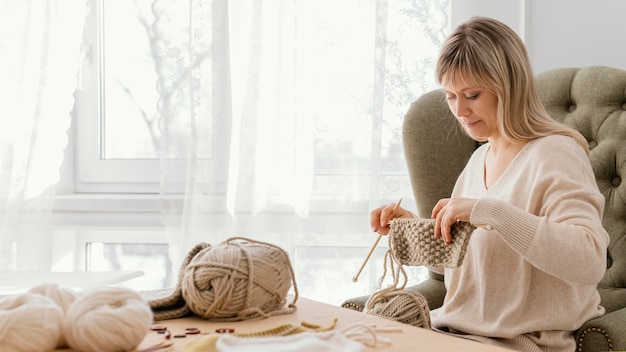 Medium shot woman holding knitted item