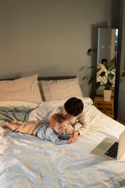 Foto colpo medio donna sdraiata a letto con il bambino