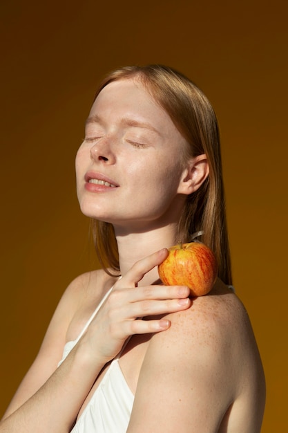 Foto donna del colpo medio che posa con la mela fresca