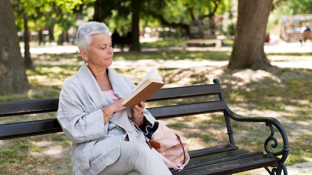 Donna del tiro medio che legge nel parco