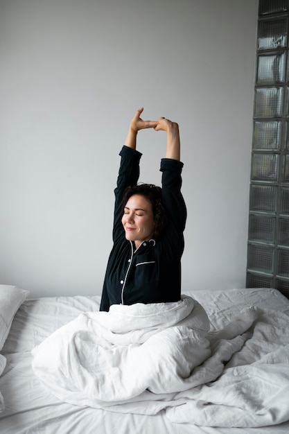 Medium shot woman stretching in bed