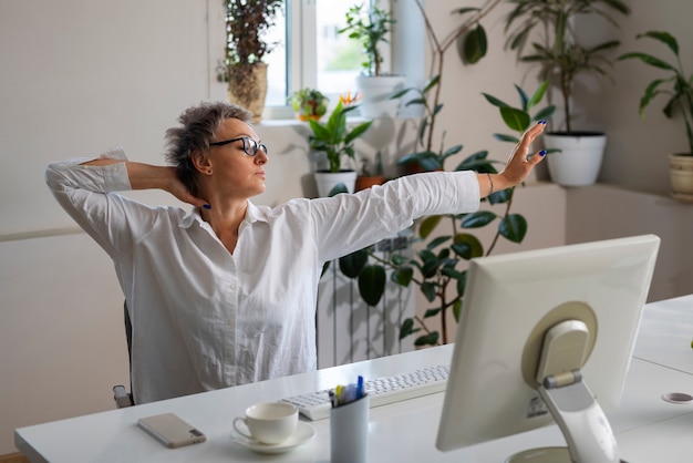 Medium shot woman stretching at desk