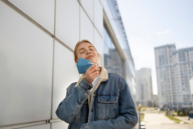 写真 マスクを脱ぐミディアムショットの女性