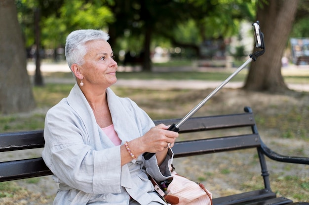 Donna del colpo medio che prende selfie all'aperto