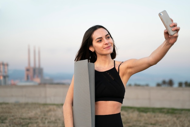 Foto donna del colpo medio che prende selfie