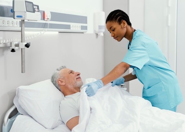 Photo medium shot woman tucking patient in bed