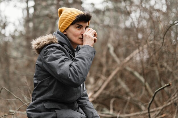 Foto donna del colpo medio con bevanda nella foresta