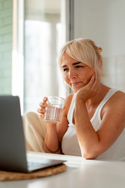 Foto donna del tiro medio con il computer portatile a casa