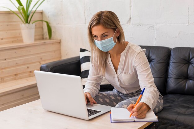 Foto colpo medio donna con maschera e laptop