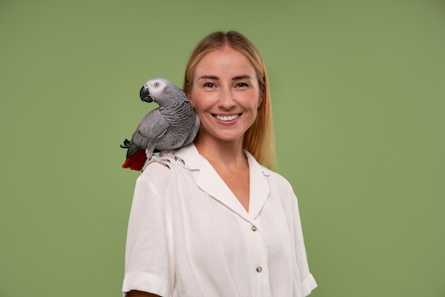 Medium shot woman with parrot in studio