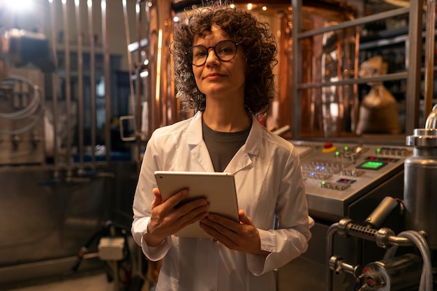 Foto donna del colpo medio che lavora nella fabbrica di birra