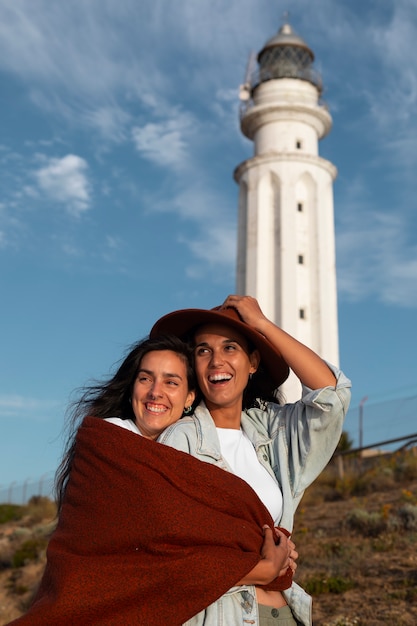 Photo medium shot women posing with lighthouse