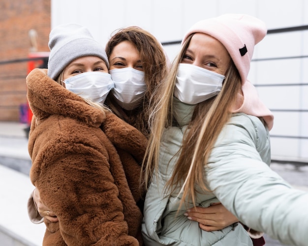 Medium shot women taking selfies with mask