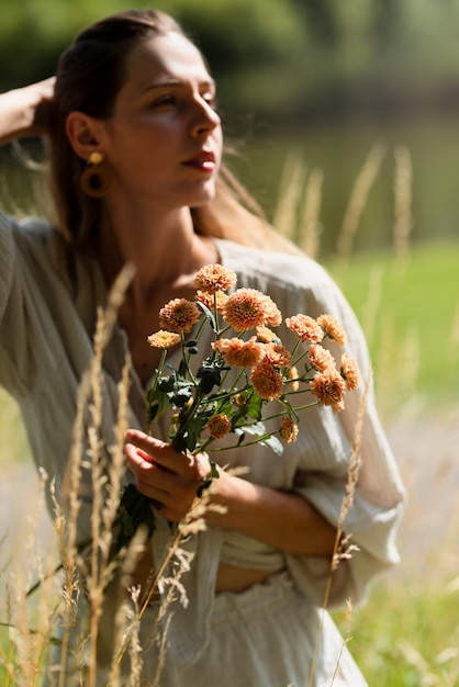 写真 花を持っているミディアムショットの若い女性