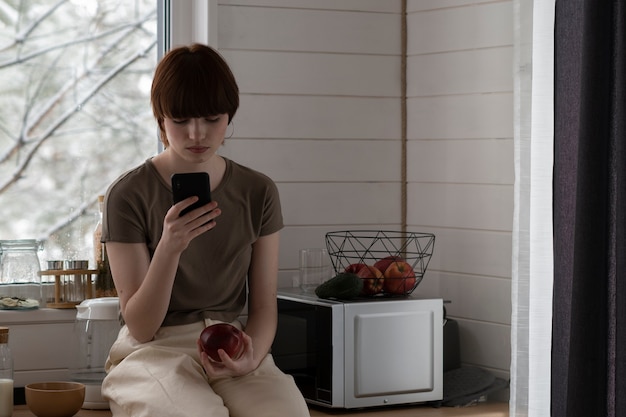 Medium shot young woman holding smartphone