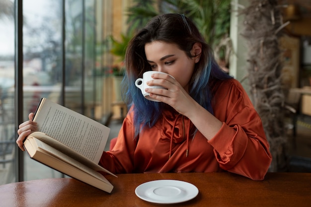 Foto giovane donna del colpo medio che si siede nella caffetteria