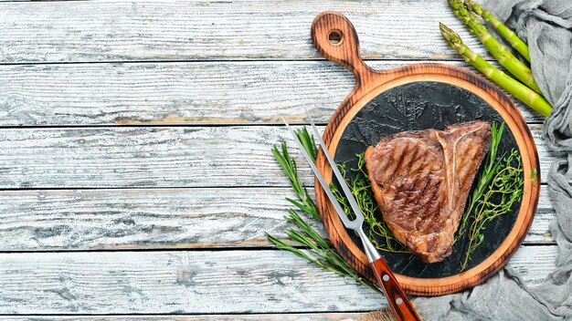 Medium zeldzame gegrilde T-Bone Steak op een witte tafel. Bovenaanzicht. Vrije ruimte voor tekst.