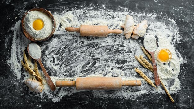 Meel eieren en deegroller bereiding van deeg bakkerij op een zwarte stenen achtergrond bovenaanzicht vrije ruimte voor tekst