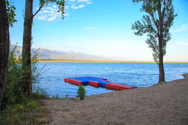 Meer in de bergen Pantone Pier Prachtige natuur weerspiegeling van wolken en bergen in blauw water Kirgizië Lake IssykKul