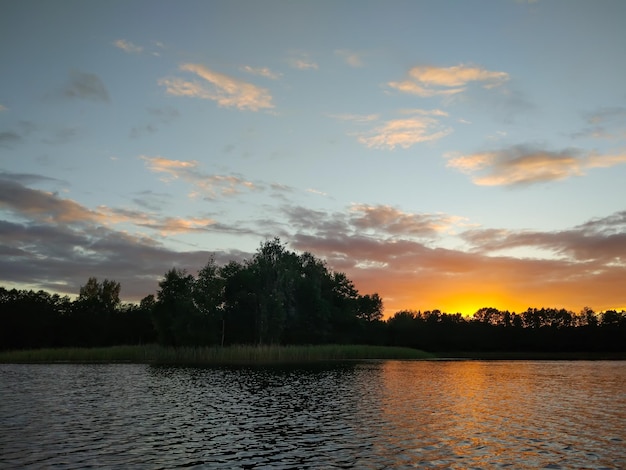 Meer in Letland met klein eiland. Zomerlandschap met kalm water, avondrood en bos.