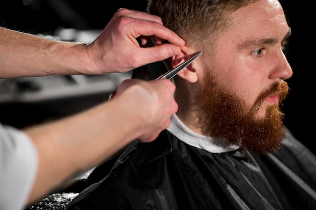 Meester knipt haar en baard in de kapper. kapper maakt kapsel met een schaar en een metalen kam.