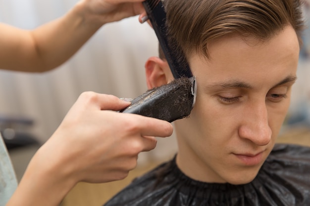 Meester knipt haar van mannen in de kapperszaak, kapper maakt kapsel voor een jonge man.